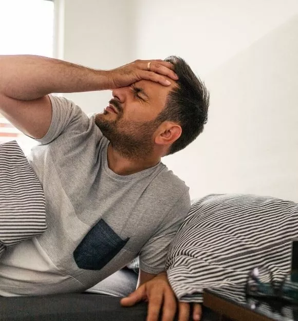 man with headache in bed